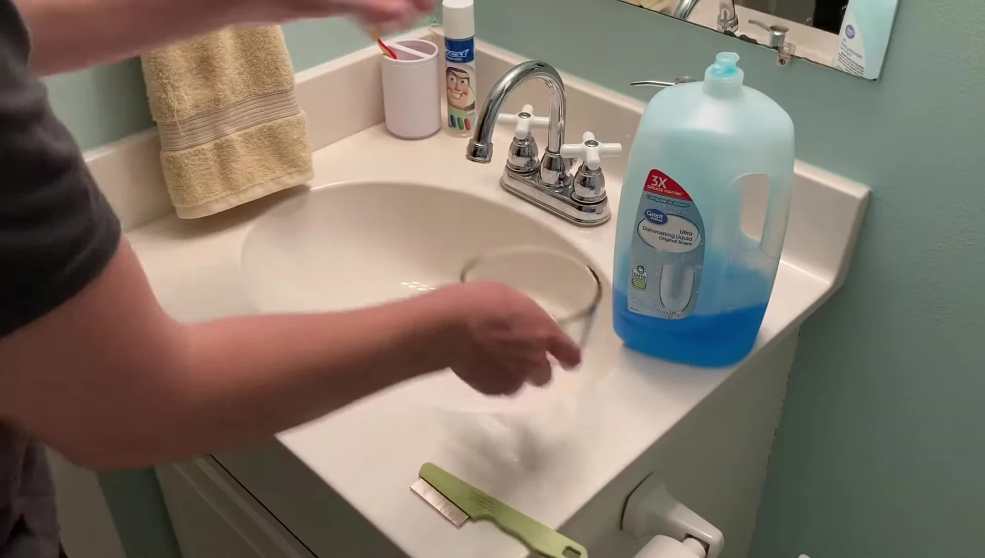 Person adding dish soap to the bowl of water