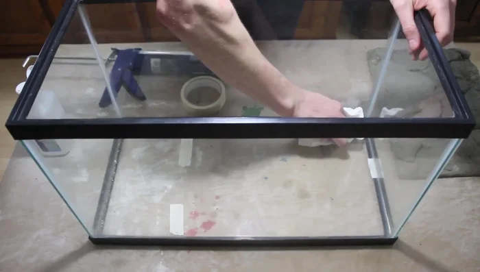 Prepare the aquarium glass with rubbing alcohol. Apply silicone to the glass, place the background firmly onto the silicone, and let it cure for at least 24 hours.