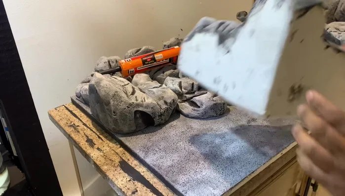 Apply a layer of silicone glue to the styrofoam board, attach the artificial rocks securely. Allow the silicone to fully dry for 24 hours.