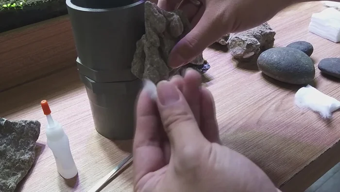 Position cotton: Insert the cotton ball into the gap between the rock and the PVC pipe, aiming for a snug fit.