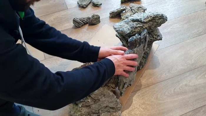 Arrange large rocks on the underlayment to create the cave structure, aiming for overhangs and crevices.