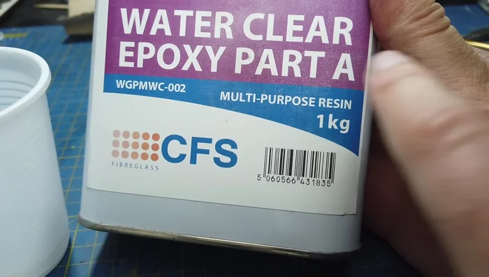 Mixing and pouring tinted epoxy resin. (Note: The video highlights the mistake of insufficient sealant for the sculpture block, leading to issues.)