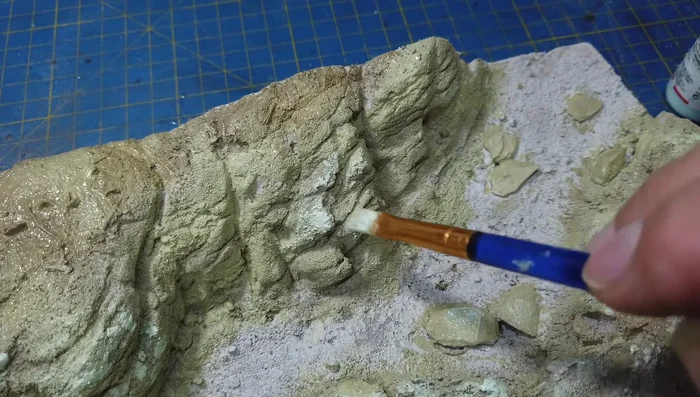 Applying a black wash to the rocks, paying attention to crevices.