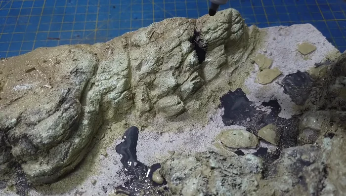 Applying a black wash to the rocks, paying attention to crevices.