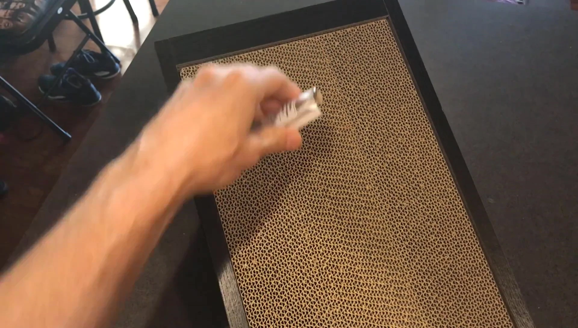 Sprinkling catnip onto the scratching pad.
