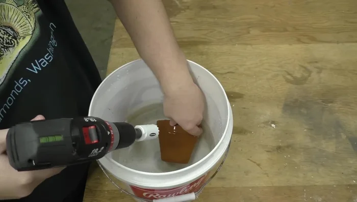 Start drilling slowly, using the pilot bit to guide the hole saw, frequently dipping the bit in water to prevent overheating.