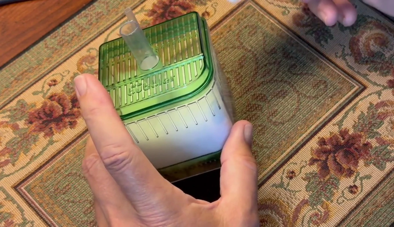 The presenter is holding a large bag of filter floss, emphasizing its cost-effectiveness.