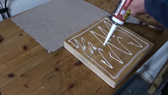 Cover the base with carpet: Apply solvent-free adhesive to the plywood base and attach carpet scraps. Secure with weights until the adhesive dries. Trim excess carpet.