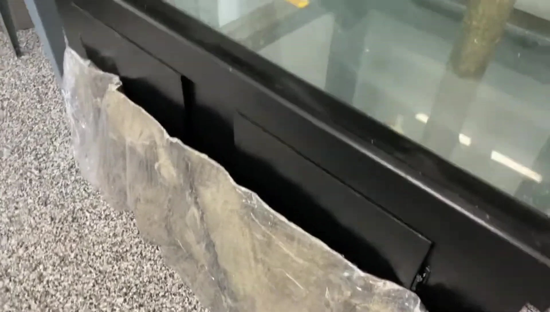 Close-up view of the speaker applying aquarium silicone to the bamboo base.