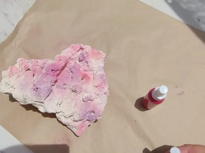 Spray the powder onto the rock, focusing on areas you want to enhance.