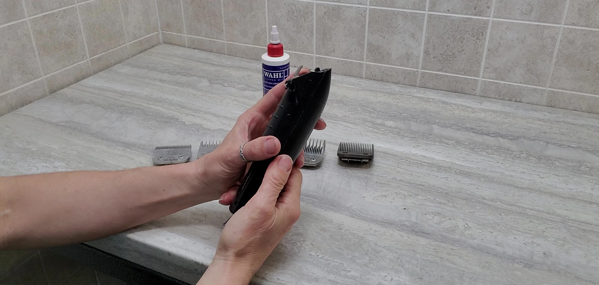 The groomer points to a part of the clippers needing replacement