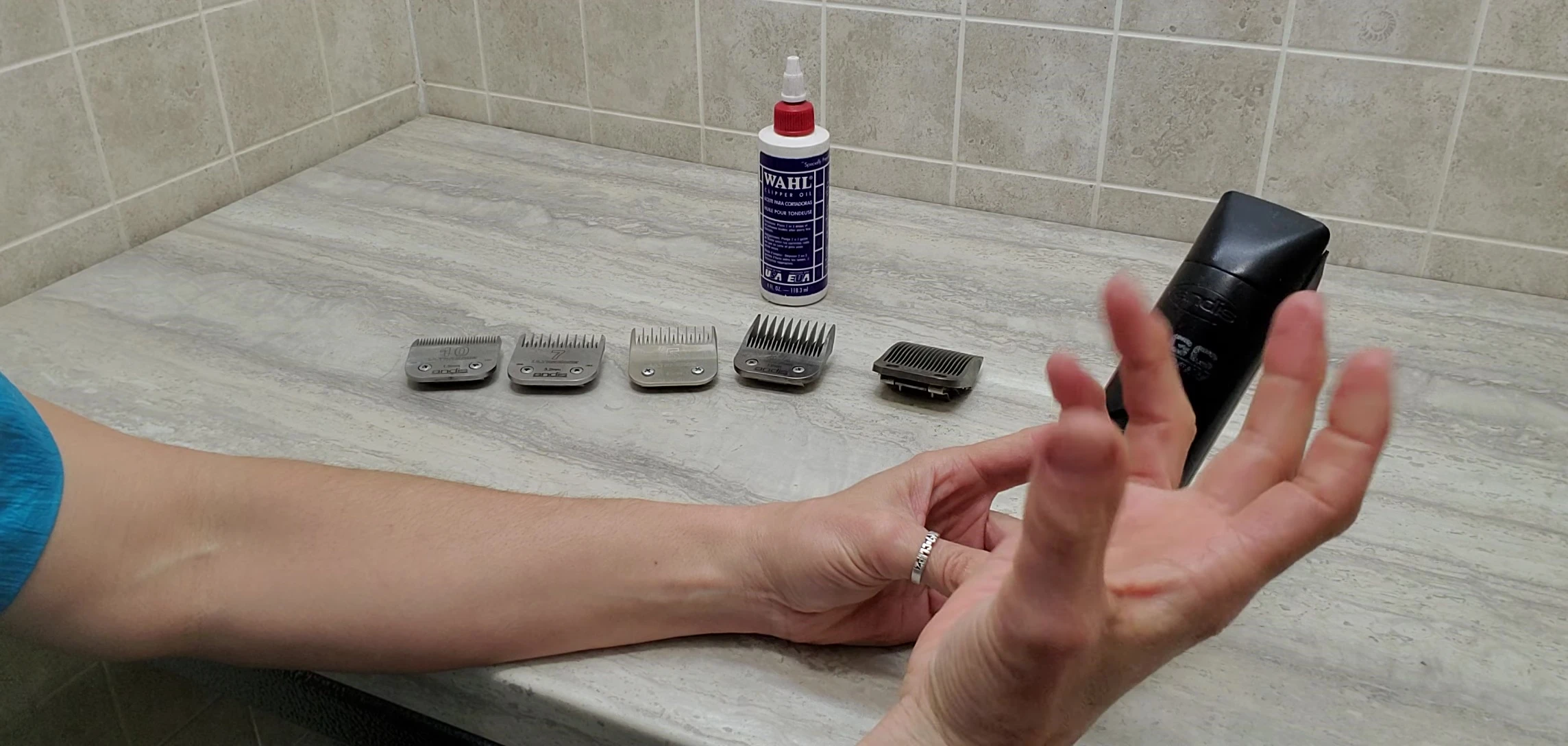 Close-up of the groomer's hands holding the Andis clippers.